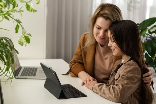 Teen girl distance learning virtual distance online class on video call virtual lesson with mother, studying at home using laptop computer. Parent or tutor helping child daughter with remote education