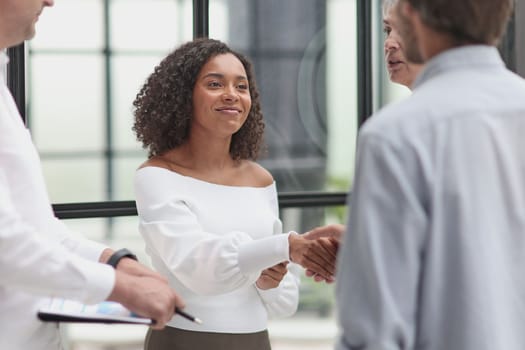 Smiling multiethnic businesspeople shaking hand in office.