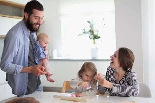 Happy parents playing with their children in the kitchen