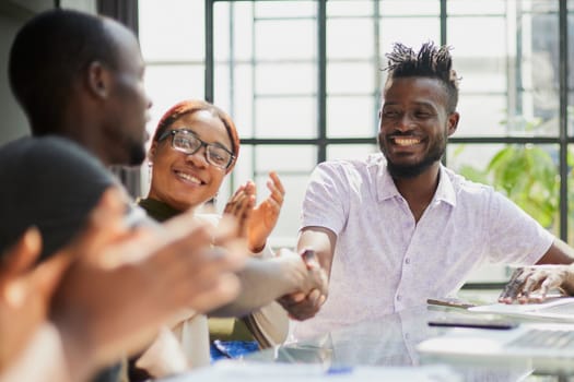 team of young african people in the office shaking hands