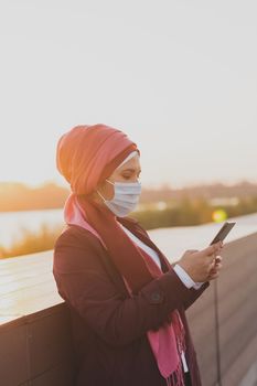 Muslim arab woman wears hijab and blue protective medical mask works online on laptop and video communication via Internet - social networks, business and video call