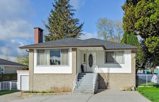 Average residential house with concrete stairs and paved front yard.