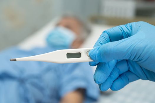 Doctor holding digital thermometer to measures asian elderly woman patient wearing a face mask have a fever in hospital, healthy strong medical concept.