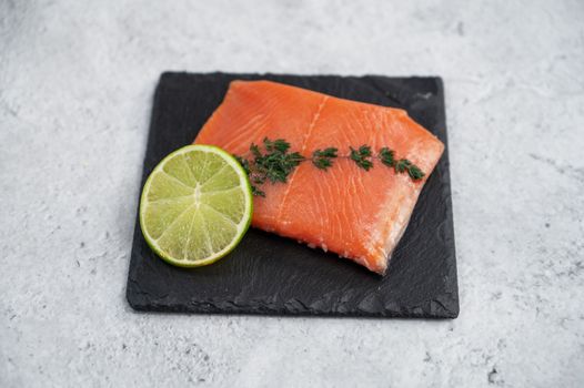 Fresh salmon with , greens and lime on concrete background