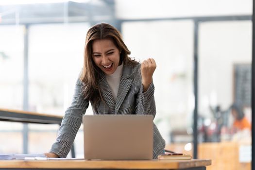 Young happy Asian businesswoman working and use laptop and thinking idea for her business.