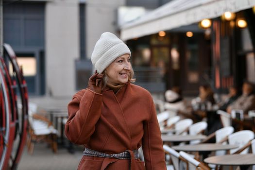 A fifty-sixty-year-old woman walks in the city
