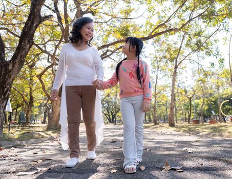 Happy grandmother and grandchild walking in public park.