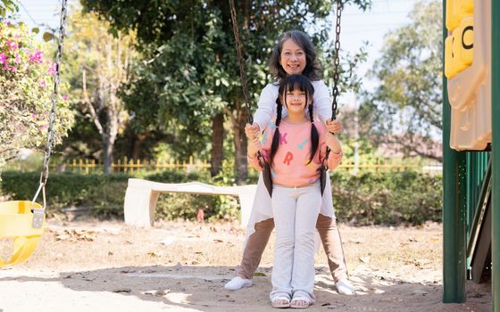 Grandmother with grandchild in playground at park.