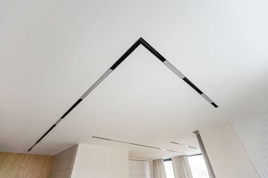 LED strip light and illumination. Also called ribbon light or LED tape to suspended on ceiling in plasterboard in empty living room include down light, white wall. Interior home design and technology.