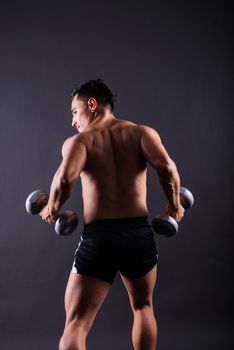 Shirtless bodybuilder showing his great body and holding dumbells.