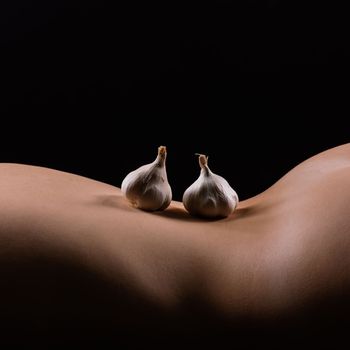 Close up of a woman back with laying garlic, low key