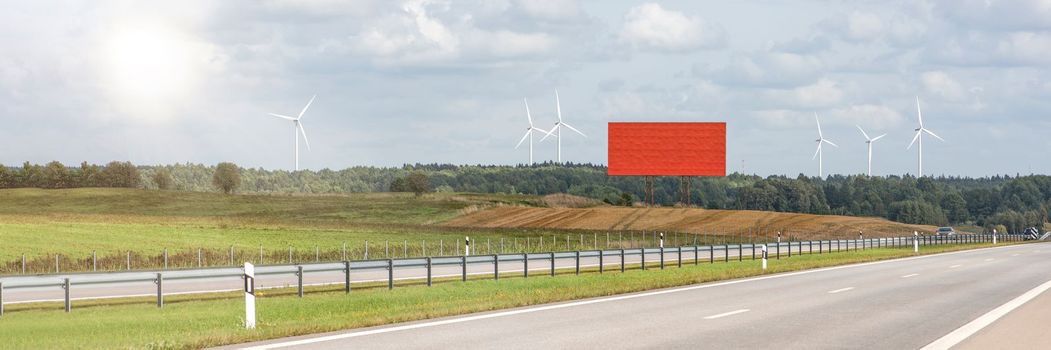 Green wind energy. Wind turbines for the production of renewable electricity. Windmills in a field produce electricity on a sunny summer day. Empty billboard to insert design, advertisement or text
