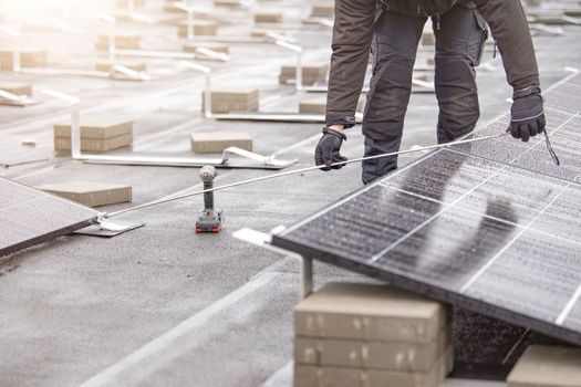 The process of installing solar panels. The installer measures the distance between solar panel modules. Green and renewable energy concept.