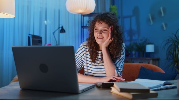 Young woman accountant working with financial graph documents, calculate taxes for charts and graph reports of home income on couch. Businesswoman working on laptop computer planning expenses budget