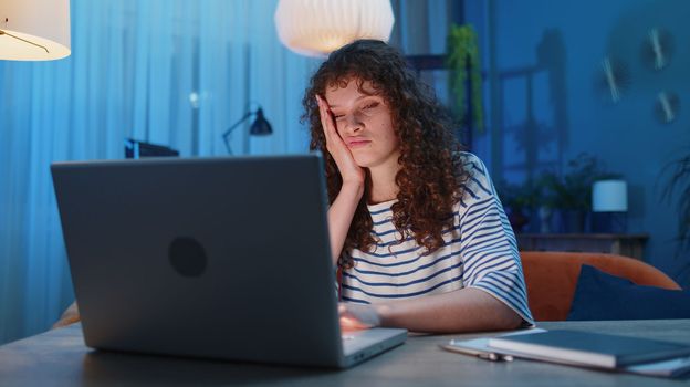 Tired young exhausted woman freelancer use laptop, suffering from headache problem tension and migraine, stress at home. Girl works on notebook, sends messages, makes online purchases, watching movies