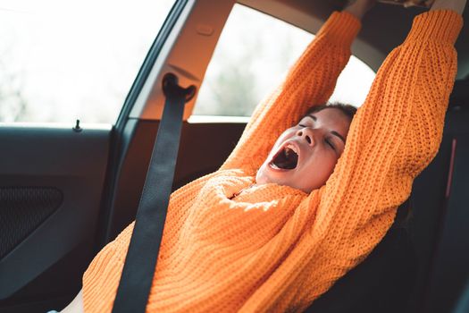 Beautiful young happy smiling caucasian woman driving in her car, wearing sunglasses and an orange sweater. High quality photo