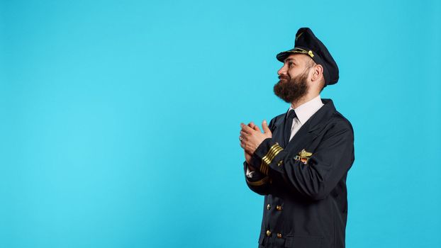 Aircrew captain pointing to left or right sides in studio, indicating direction sideways and working on commercial flights. Male model dressed as airplane pilot having professional occupation.