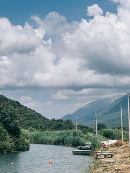 Fishing boats lie on the banks of the river overgrown with reeds at the foot of the mountains. High quality photo