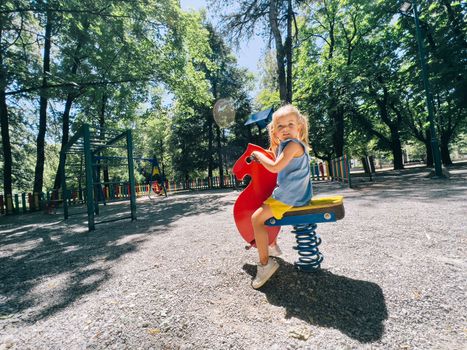 Little girl sitting on a swing-spring in the playground. High quality photo