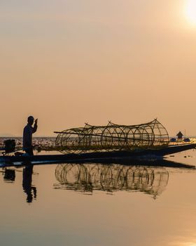 Fishermen in a boat at Sunrise at The sea of red lotus, Lake Nong Harn, Udon Thani, Thailand February 2023