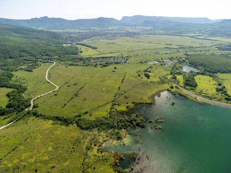 Aerial landscape from flying drone storage reservoir at mountain foot covered colorful spring forest. Beautiful view from above blue lake among highlands