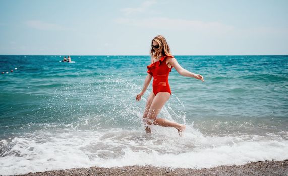 Young happy woman walks carefree on the seaside. Happy lady in red bikini. Portrait beautiful young woman relax smile around beach sea ocean in holiday vacation travel trip.