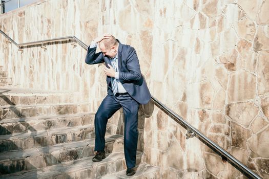 Portrait of a senior professional man in a suit with various problems. A middle-aged businessman with a briefcase descends the stairs.