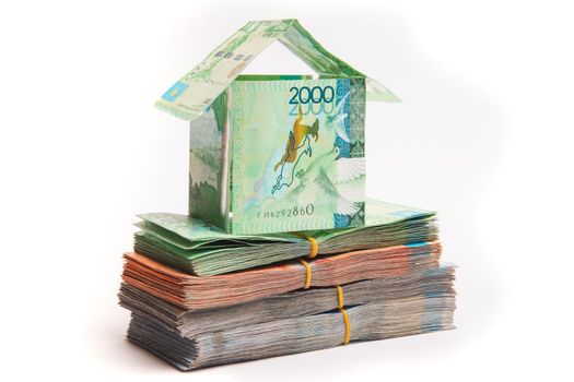 House made of banknotes of Kazakh money stands on packs of tenge. Mortgage concept, real estate appreciation, isolated on white