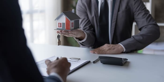 Real estate agent is discussing and explaining the terms of the home purchase contract. Businessman signing a contract agreement, mortgage, rent, lease, home insurance...