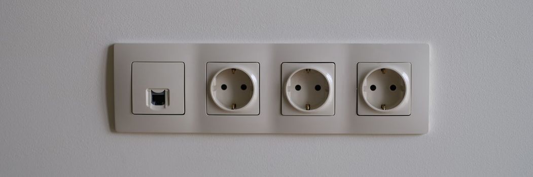 Electric socket on white wall closeup. Sockets with antenna cable and internet concept