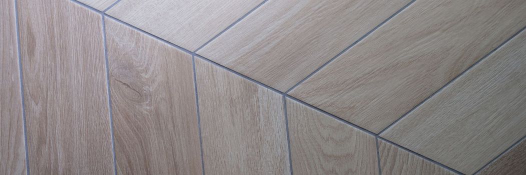 Oak texture of floor with tiles imitating parquet. Traditional herringbone pattern on wooden floor concept