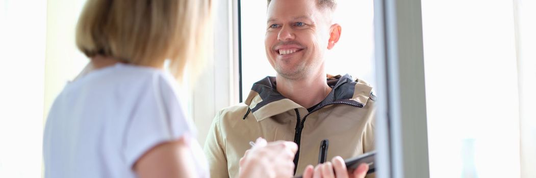 Woman signs on a tablet for parcel from courier at home. Delivery of goods and logistics concept