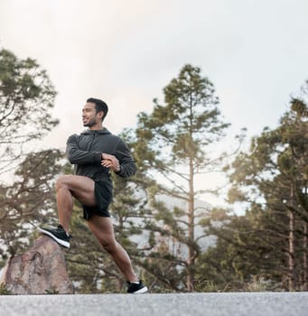 Prepping for his trail run. a sporty young man stretching his legs while exercising outdoors