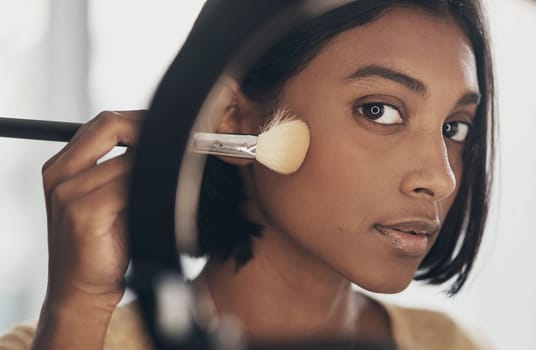 Beauty is in the eye of the makeup brush holder. a young woman applying makeup while filming a beauty tutorial at home