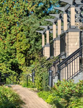 Porches of residential townhouses in a row with paved pathway in front.