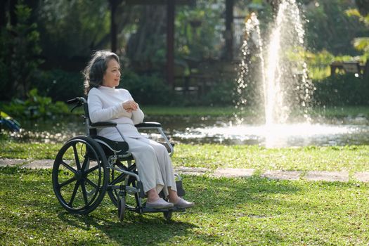 Elderly asian senior woman on wheelchair with nurse. Nursing home hospital garden concept