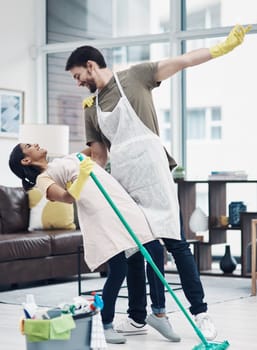 Redefine what romance really is. a happy young couple dancing while mopping the floor at home