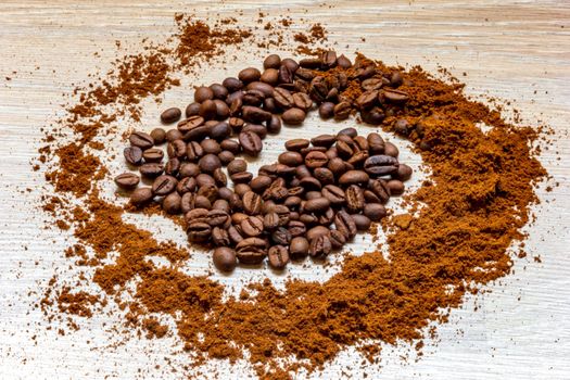 Coffee beans and ground coffee on a wooden table like a spiral.  Vintage style concept