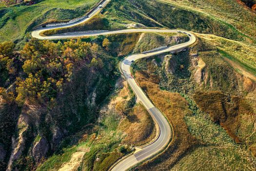 Aerial photo of a curved mountain road under the mountain peak.