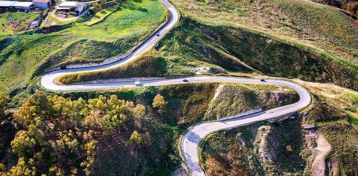 Aerial photo of a curved mountain road under the mountain peak.