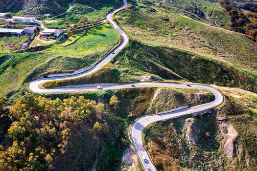 Aerial photo of a curved mountain road under the mountain peak.
