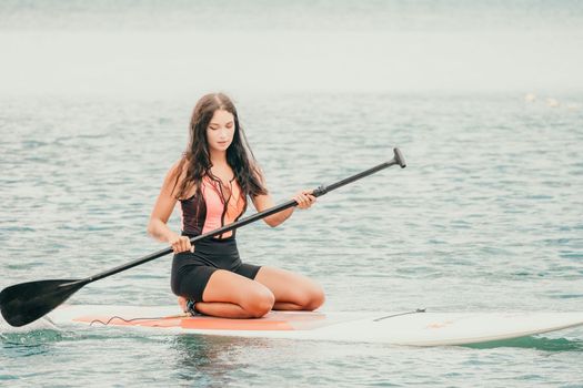 Close up shot of beautiful young caucasian woman with black hair and freckles looking at camera and smiling. Cute woman portrait in a pink bikini posing on a volcanic rock high above the sea