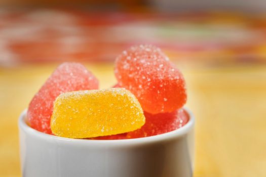 Red and yellow sugar fruit candies  in white bowl ,ready to eat unhealthy sweets