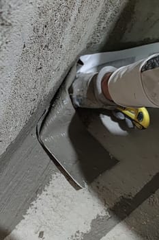 a worker sticking bathroom waterproofing tape on a corner.