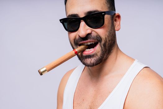 Close-up bearded caucasian man smoking cigar. Wearing white shirt. Studio portrait