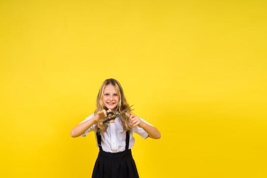 Teenage school girl with scissors, isolated on yellow background. Child creativity, art and crafts.