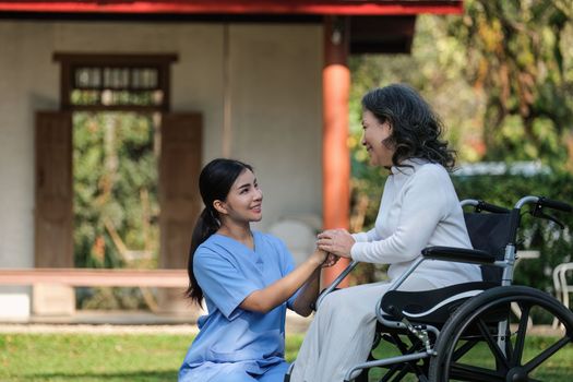 Elderly asian senior woman on wheelchair with nurse. Nursing home hospital garden concept