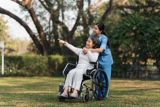 Elderly asian senior woman on wheelchair with nurse. Nursing home hospital garden concept