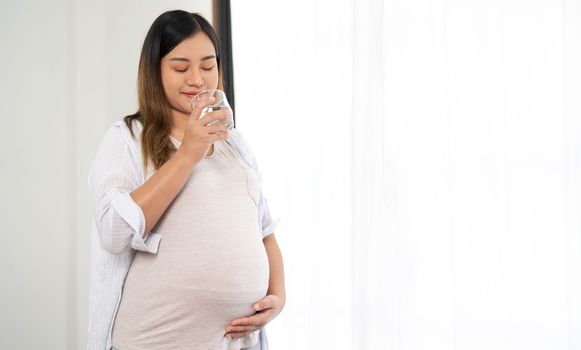 Pensive pregnant woman drinking water. Young happy expectant thinking about her baby and enjoying her future life. Motherhood, pregnancy.