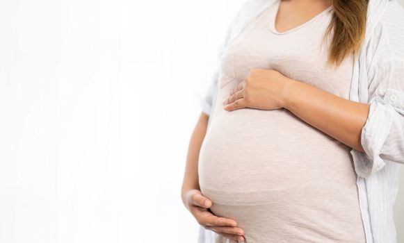 pregnant woman standing near window at home.